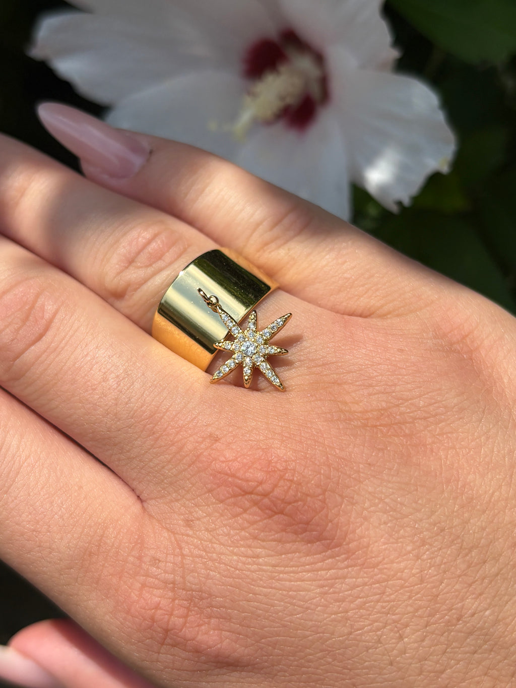 Bague large dorée avec breloque étoile en strass portée à la main