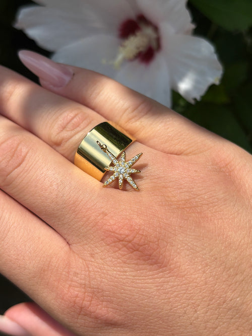 Bague large dorée avec breloque étoile en strass portée à la main