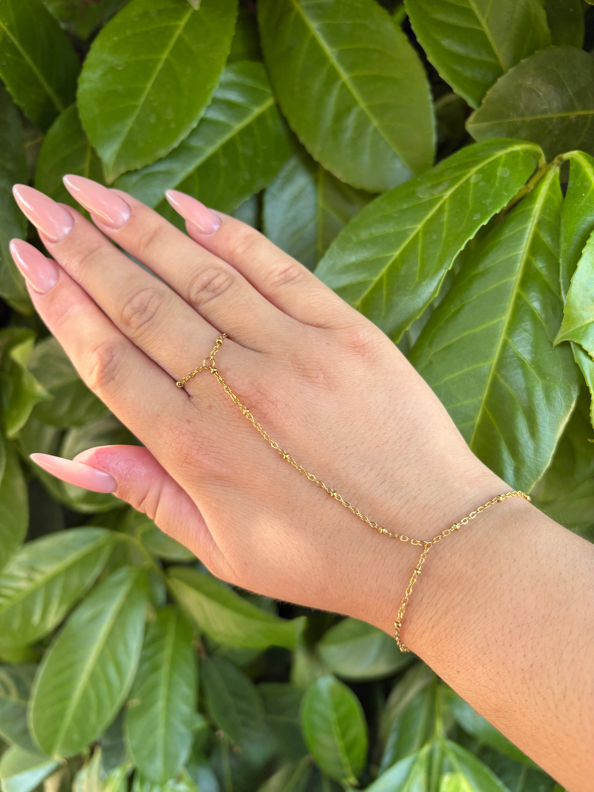 Bracelet-bague chaîne dorée portée sur la main