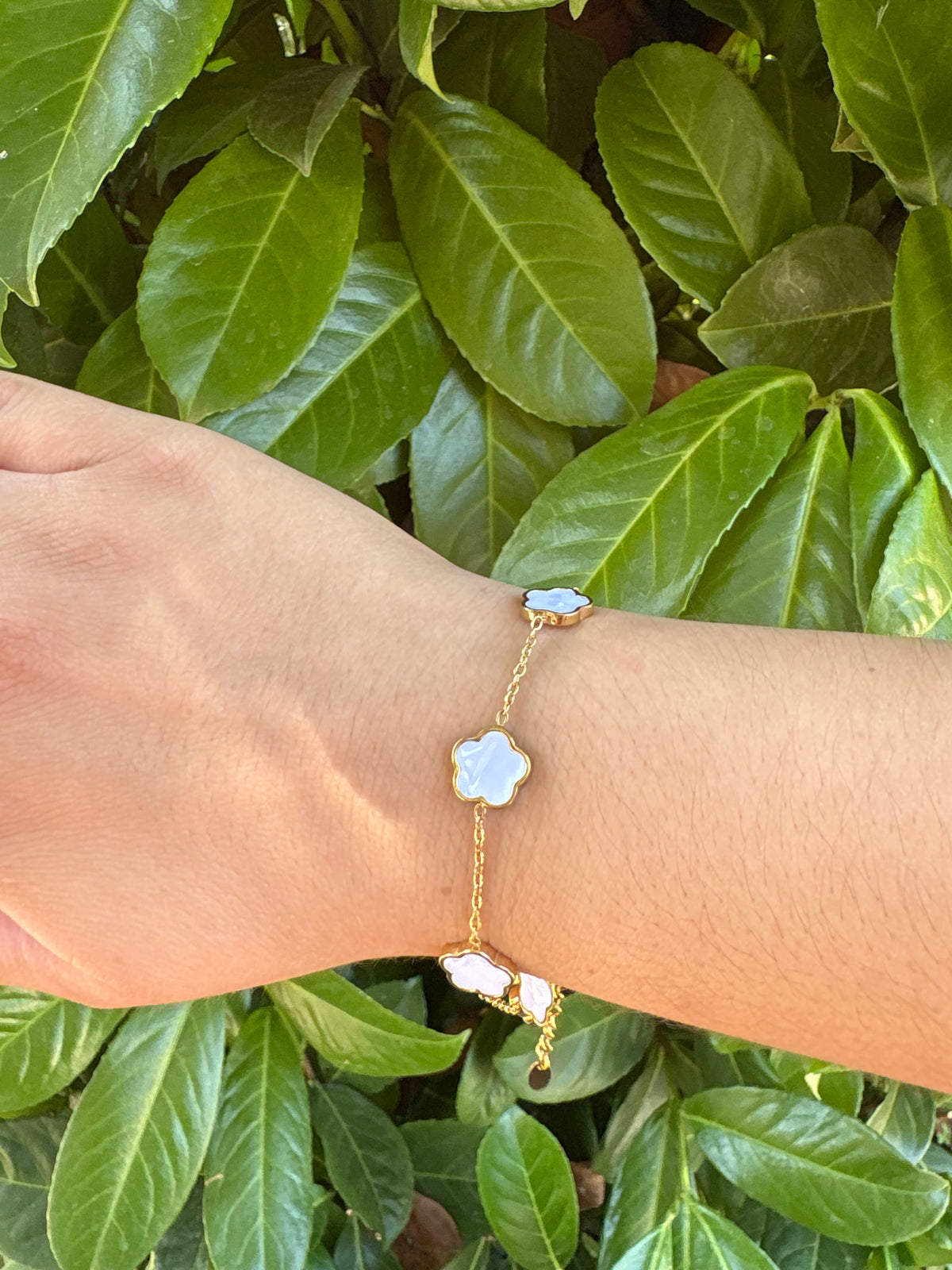 Bracelet fleurs blanches nacrées doré porté au poignet