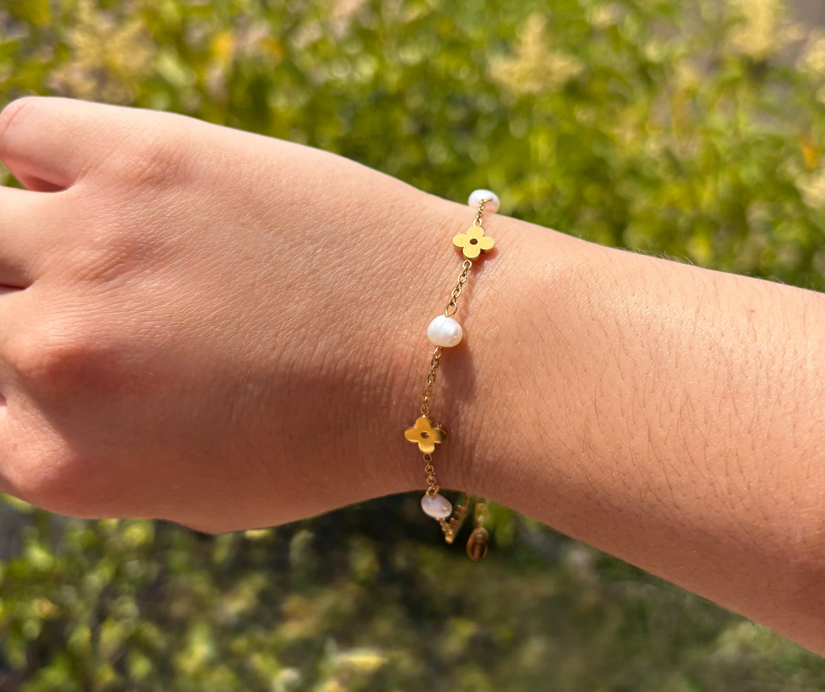 Bracelet fleurs dorées et perles blanches porté au poignet
