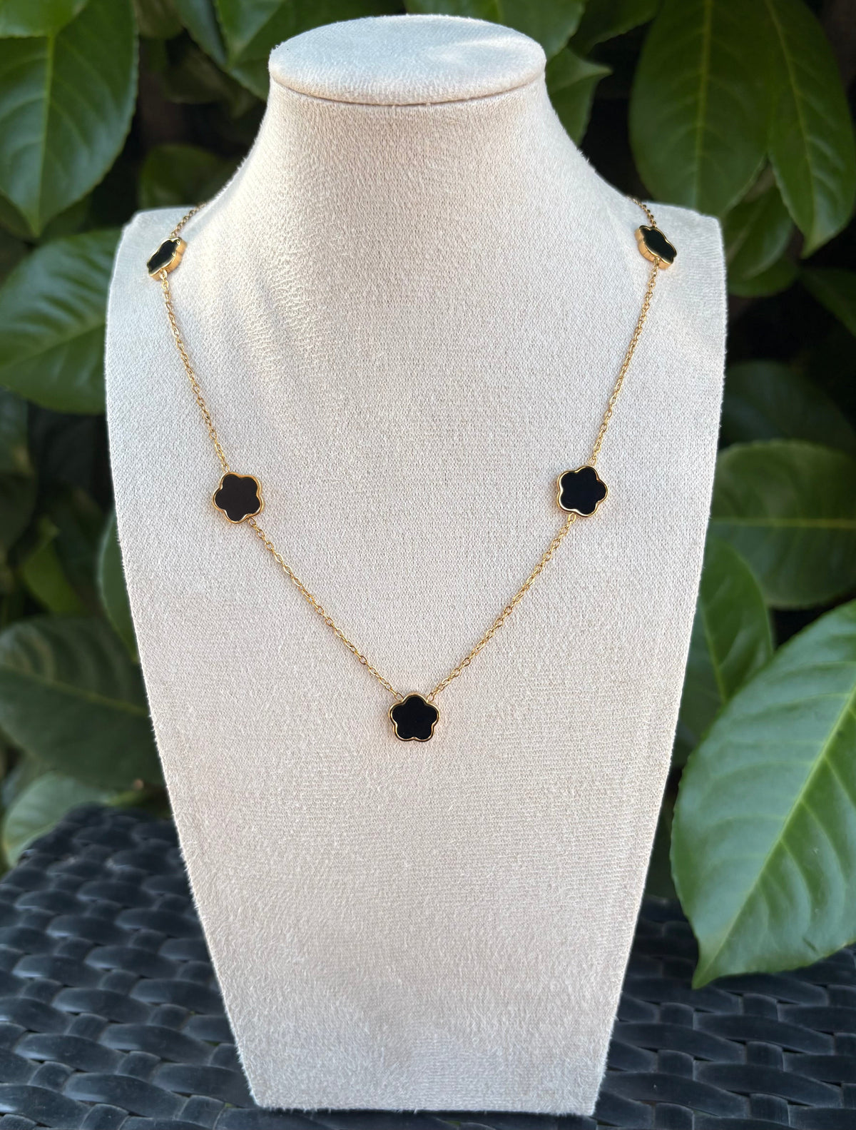 Collier fleurs noires doré sur présentoir