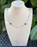 Collier fleurs dorées et perles blanches sur présentoir